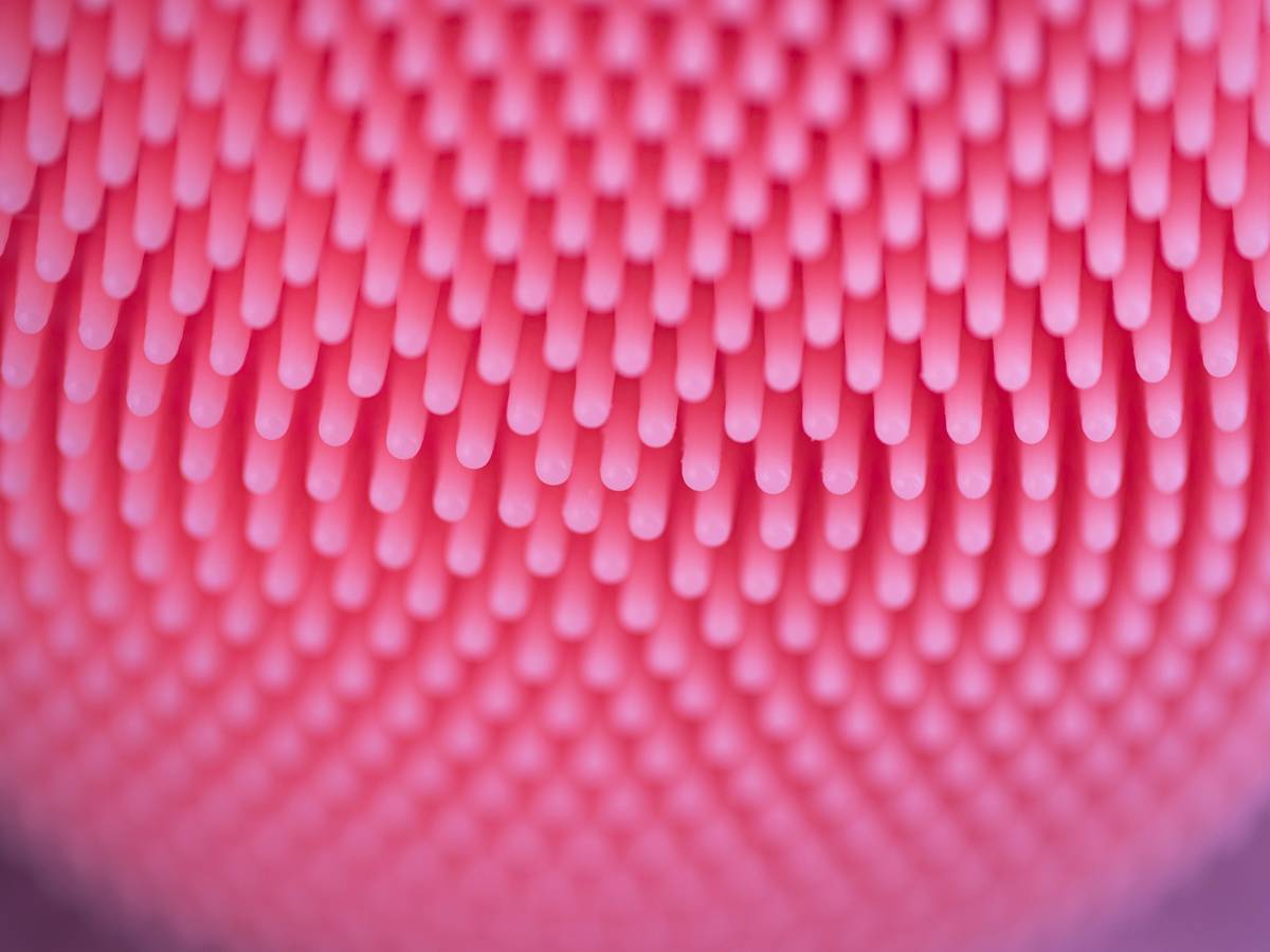 A close-up of a pink silicone face brush