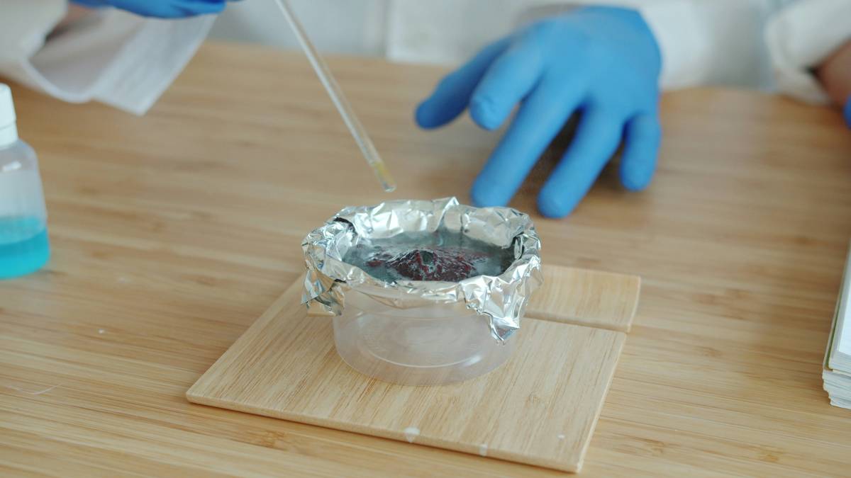 Close-up of heat resistant chemical gloves handling a hot cast-iron skillet and chemical cleaning bottle