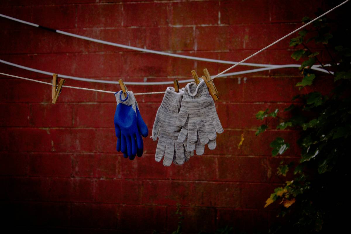 how to sanitize reusable cleaning gloves: close-up of rubber gloves being rinsed under running water with vinegar and baking soda nearby